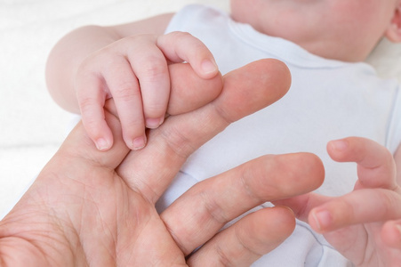 新生婴儿护理概念。男人握着的婴儿的手