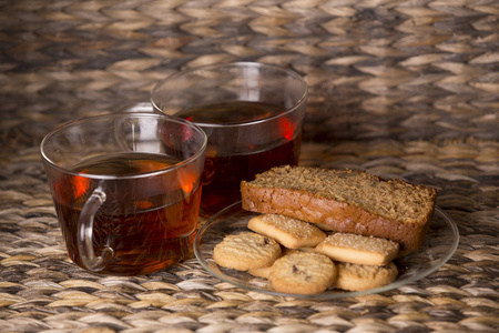 茶，饼干和蛋糕在一个木制的背景前的木桌上