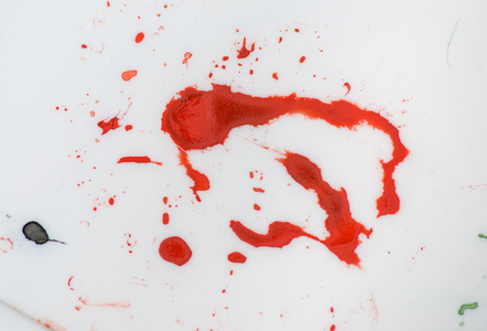 红色油漆飞溅的白色塑料的垃圾纹理。照片