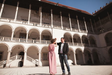 美丽的夫妇，男人，女孩粉红色的长礼服摆在列附近的古城堡。克拉科夫 Vavel