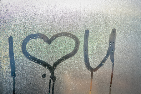 特写镜头上我爱你符号在雾的窗户玻璃背景上绘制照片