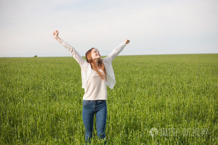 在上午的绿色麦田张开双臂的女人