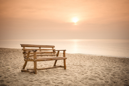 有日出背景的海滩上的旧木凳