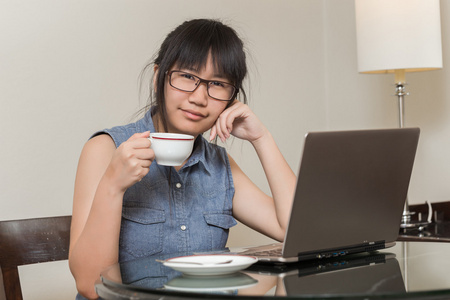 亚洲女人戴着眼镜坐在椅子上在家里