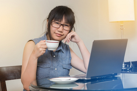 亚洲女人戴着眼镜坐在椅子上在家里