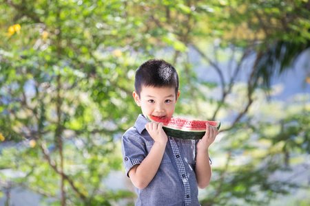 可爱的小亚洲男孩在公园里吃西瓜