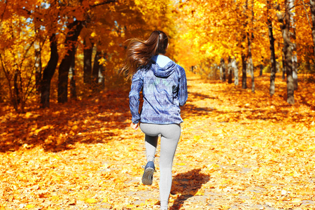 在秋天的公园慢跑的女人