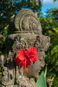 巴厘岛乌布巴利花园里有红花的巴厘岛雕塑。 印支