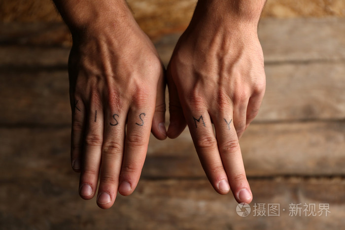 男性的手指上的纹身题字