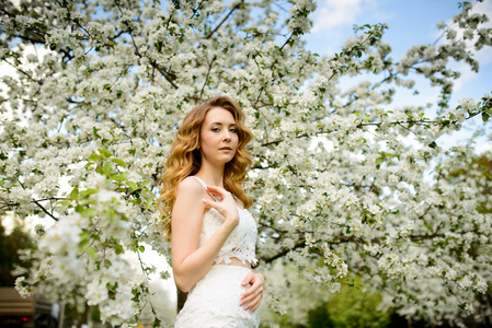 春天美丽的女孩, 金发女郎, 站在一个盛开的苹果果园