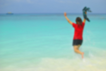 模糊快乐的女孩跳在热带海滩