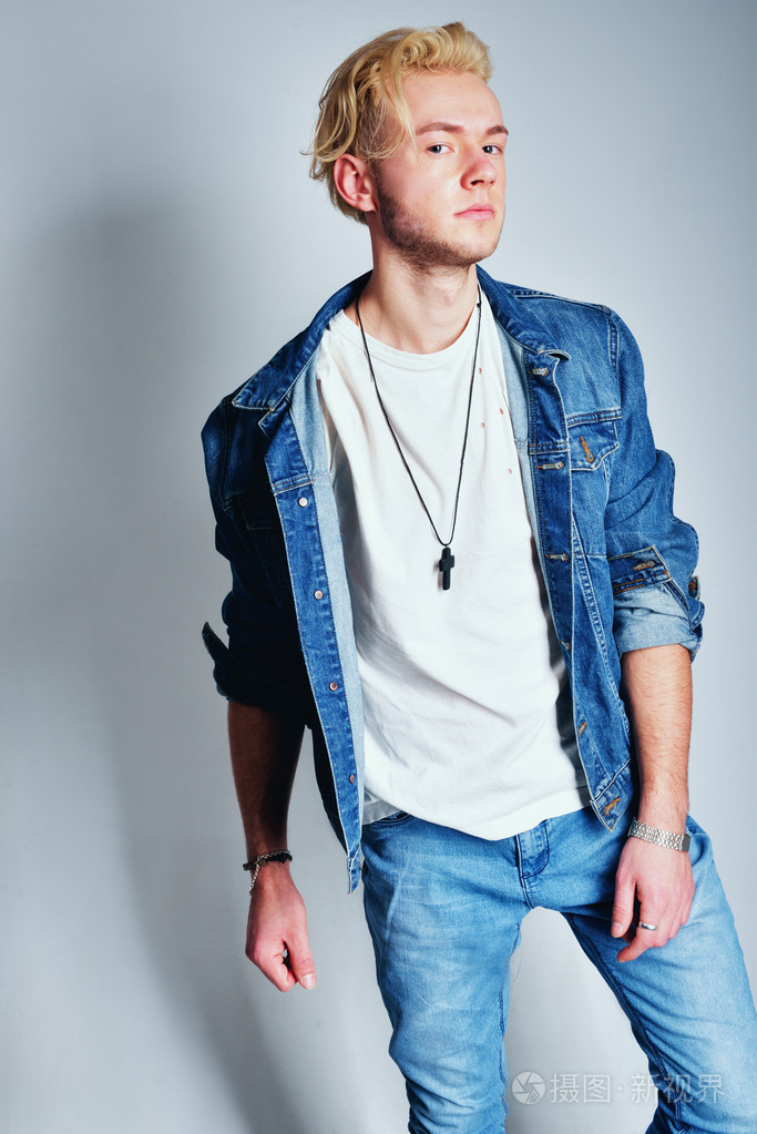 年轻时尚帅气男模特与夹克在他肩上.全身长的画像孤立在白色的背景