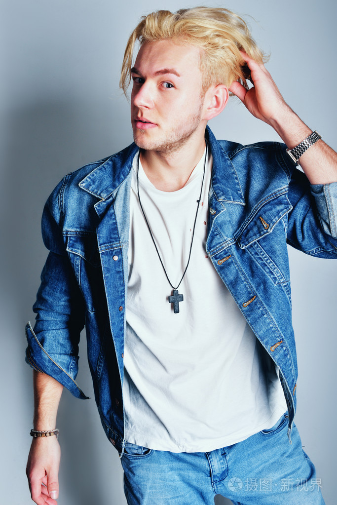 年轻时尚帅气男模特与夹克在他肩上.全身长的画像孤立在白色的背景照