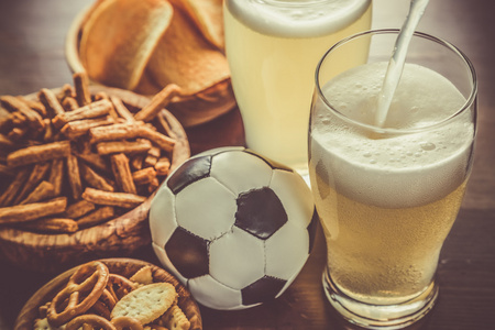 啤酒倒入玻璃小吃与足球