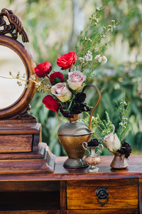 婚礼。装饰。粮食。图稿。草坪上矗立着一个老式的木桌，桌上的鲜花和绿叶组成