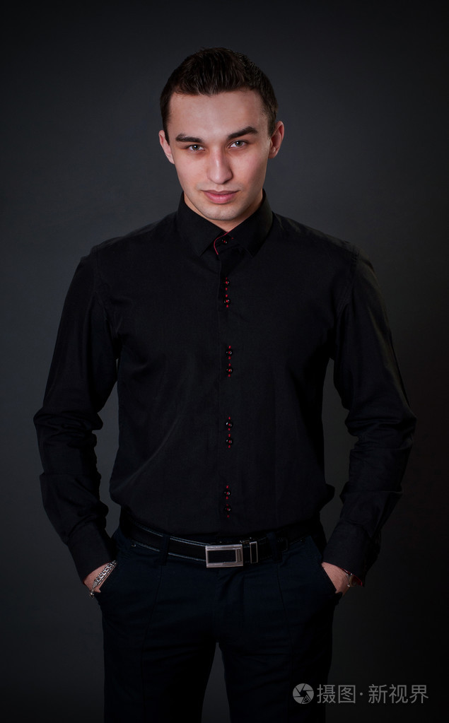 英俊的男人在录音室里的黑色衬衫姿势的时尚肖像