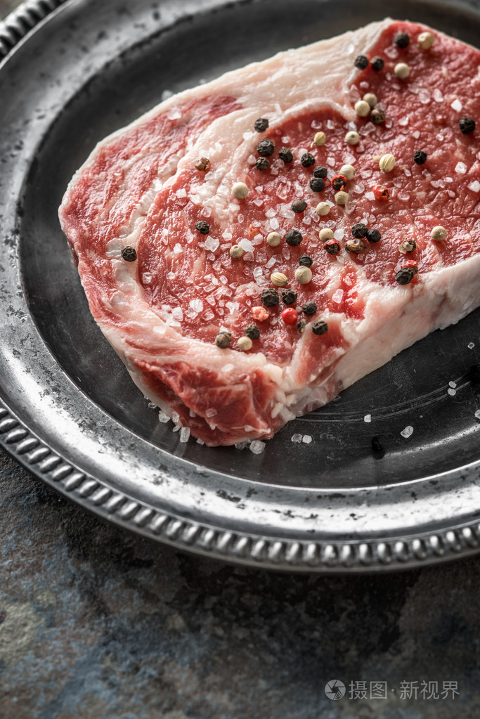 一块的肋眼牛排, 胡椒和盐放在锡 o 一盘
