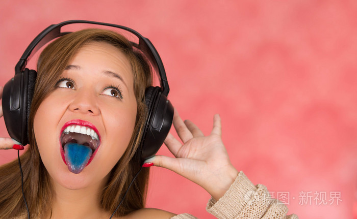 女人大声尖叫,手里拿着她的耳机,蓝舌头与牙齿照片-正版商用图片1nueq