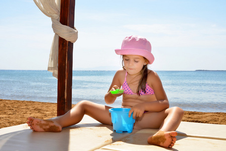 可爱的蹒跚学步的女孩在海滩享受她的暑假
