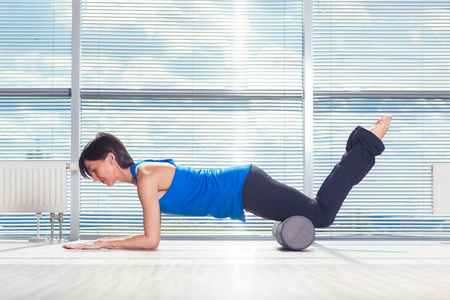 健身 运动 训练和生活方式的概念   做普拉提与泡沫辊地板上的女人