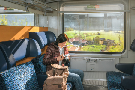 女孩骑在一辆火车上,看着照相机上的图片.查看在窗外照片