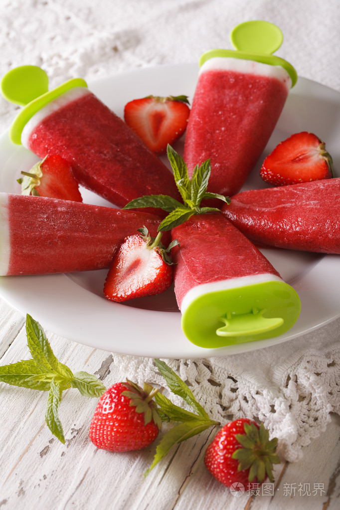 酸奶和薄荷上棍子特写的草莓冰糕垂直