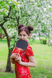 美丽的亚洲女孩，用传统的中国红礼服的风扇