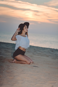 帽子和短裤享受日落海滩背景美丽幸福的女人的画像