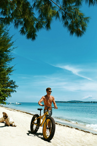 在海滩上骑沙自行车的人。 夏季体育活动