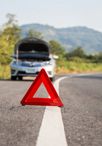 红色紧急停止标志和在道路上的破的车