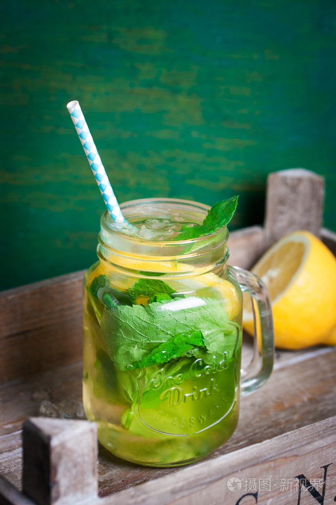 美味多彩饮料与冷绿茶, 薄荷, 柠檬放在玻璃缸