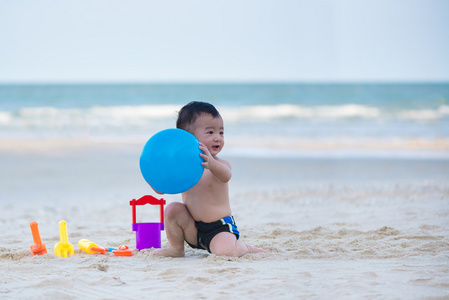 亚洲小孩 1 岁在沙滩上玩球