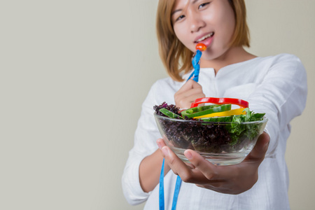 美丽的女人吃沙拉叉卷尺包裹