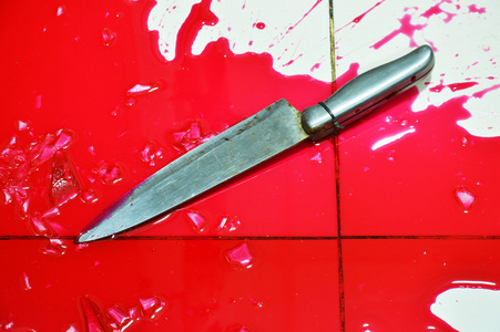 刀和大量的血液飞溅在瓷砖地板上照片