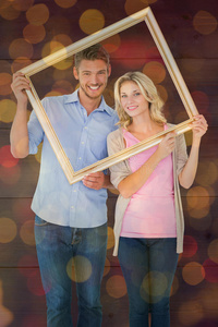 吸引人的年轻夫妇抱着相框的复合图像