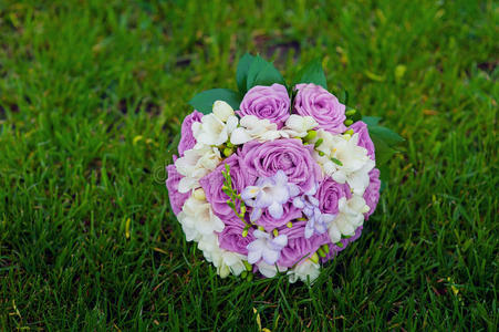 草地上紫色玫瑰的新娘花束