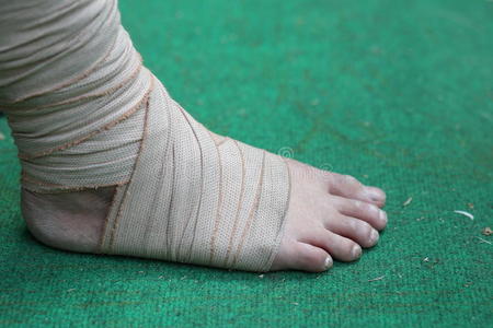 脚和脚踝在绿色背景上用绷带受伤照片