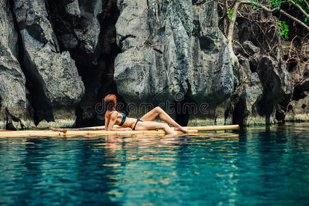 美丽的女人在热带泻湖的木筏上放松