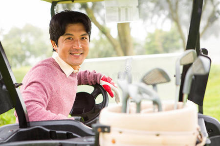 快乐的高尔夫球手开着高尔夫球车对着镜头微笑
