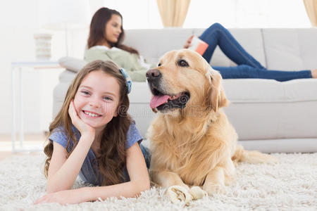 女孩带着狗在地毯上，而母亲在家里放松