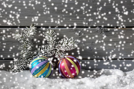 五颜六色的圣诞球在一堆雪上靠在木墙上