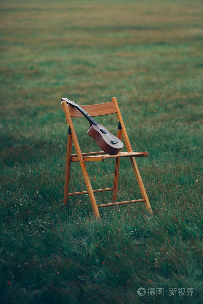 小吉他站在大自然的草地上椅子上