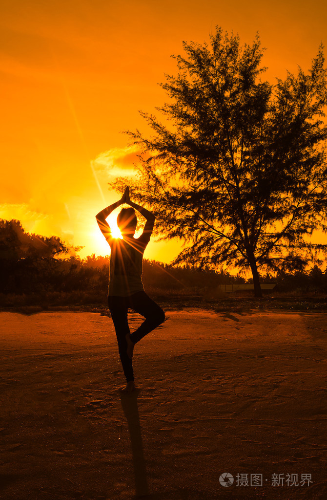 剪影年轻女人在阳光与沙滩上玩瑜伽