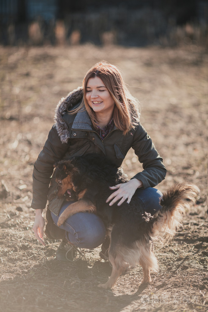 女孩玩一条狗在后院的阳光