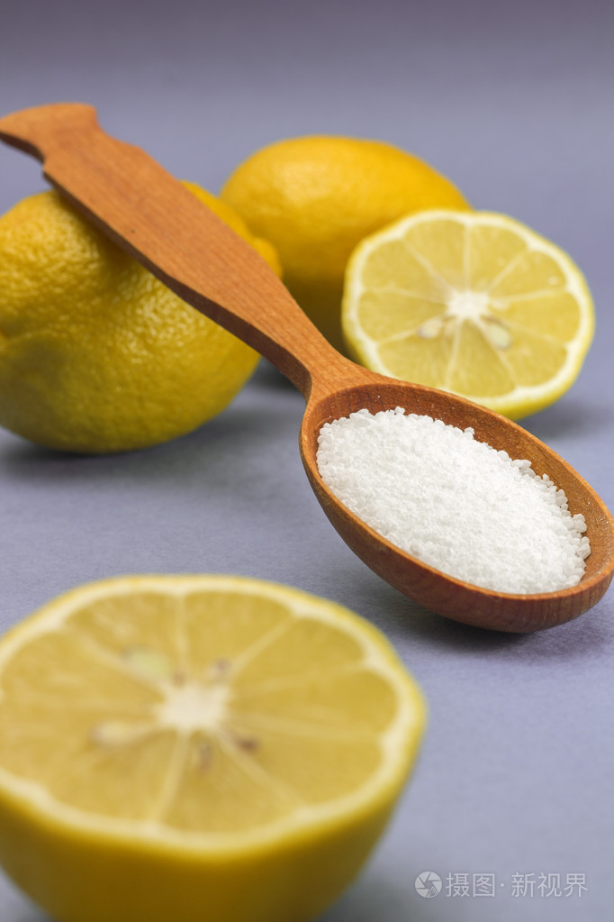柠檬酸在木勺在蓝色背景
