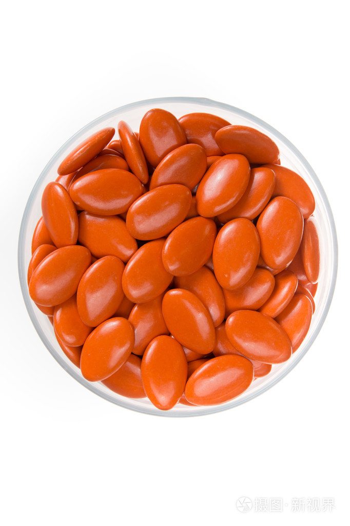 橙色糖衣杏仁糖衣药片在玻璃盘上白色孤立