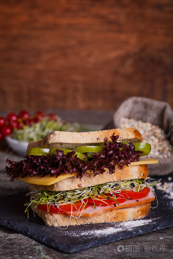三明治配生菜谷物面包, 片新鲜的西红柿和甜辣椒, 火腿, 火腿, 香肠
