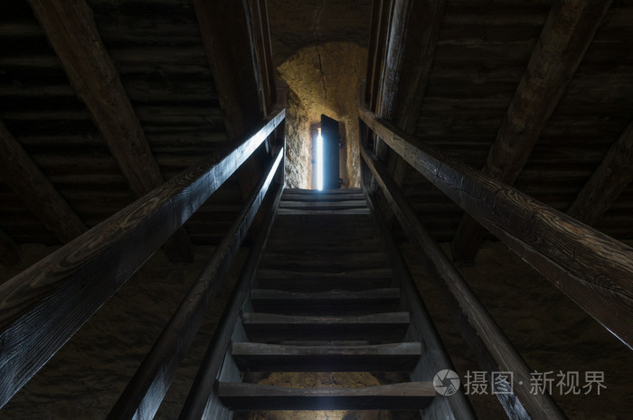 黑暗的房间里石墙窗口与木制楼梯