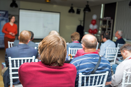 介绍嘉宾发表演讲的女人.观众在会议演示文稿照片