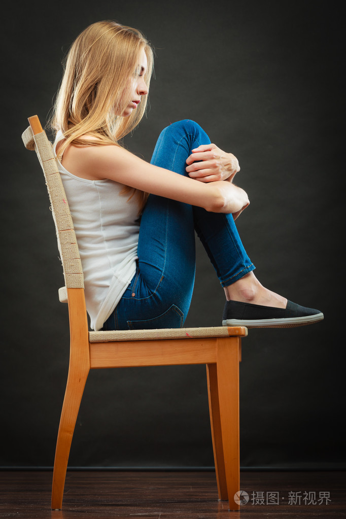 年轻的伤心女人坐在椅子上